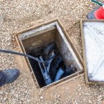 Technician inspecting trenchless pipe repair equipment in a maintenance access point, illustrating advanced plumbing solutions by Jersey Trenchless LLC.